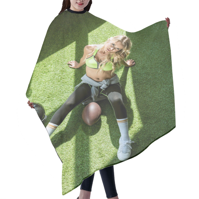 Personality  Overhead View Of Sporty Young Woman Sitting On Green Grass With American Football Ball And Helmet Hair Cutting Cape