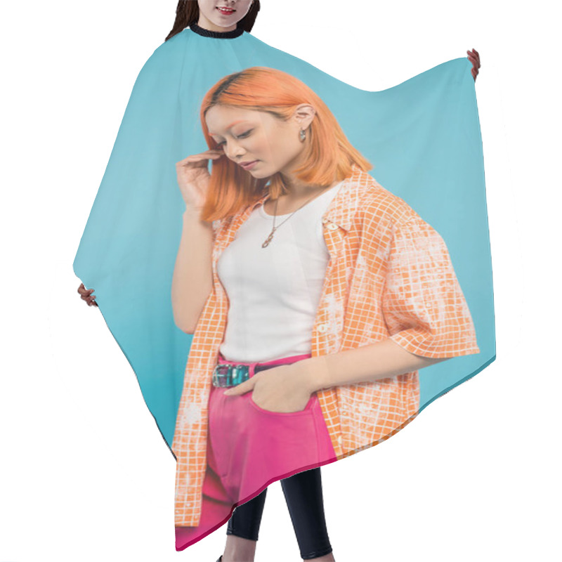 Personality  Hand In Pocket, Sensual And Young Asian Woman With Dyed Hair Standing In Orange Shirt And Posing On Blue Background, Looking Away, Pink Pants, Generation Z, Modern Style  Hair Cutting Cape