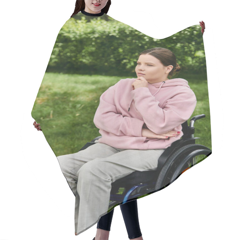 Personality  A Young Woman In A Pink Hoodie Sits Thoughtfully In A Wheelchair Outdoors. Hair Cutting Cape