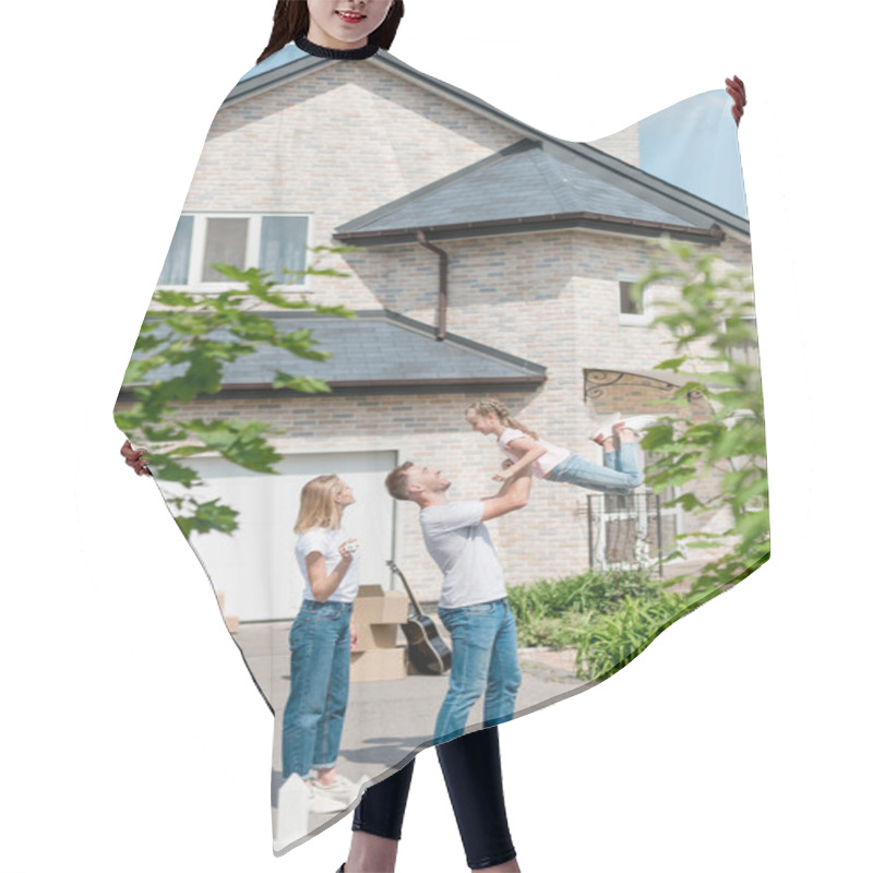 Personality  Side View Of Father Raising Up Daughter While Mother Standing Near In Front Of Their New House  Hair Cutting Cape