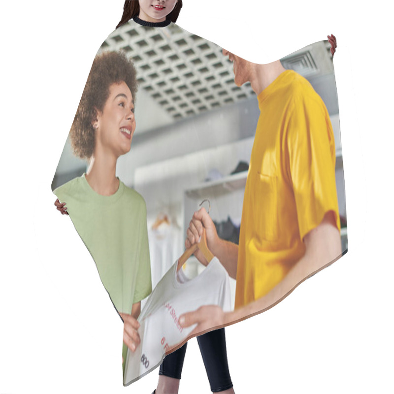 Personality  Smiling Young Multiethnic Designers Talking And Looking At Each Other While Holding T-shirt With Lettering On Hanger And Working In Print Studio, Start-up Innovation Concept Hair Cutting Cape