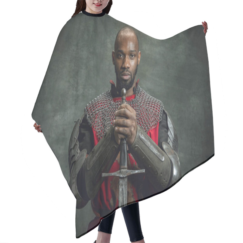 Personality  Vintage Portrait Of Dark Skinned Medieval Warrior Wearing Chain Mail Holding Big Sword Isolated Over Dark Vintage Background. Comparison Of Eras, History. Side View Hair Cutting Cape