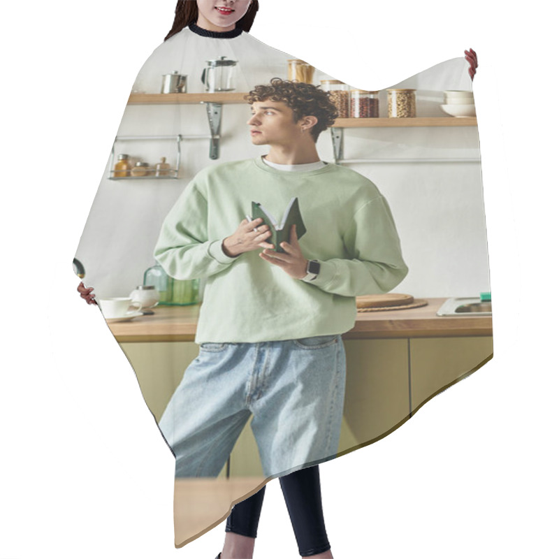 Personality  The Handsome Young Man In A Cozy Kitchen Contemplates While Holding Fresh Green Vegetables, Exuding Creativity. Hair Cutting Cape