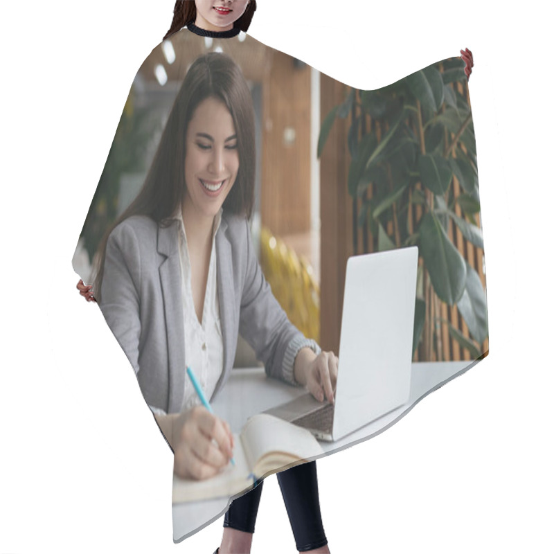 Personality  Portrait Of Smiling Successful Businesswoman Working In Modern Office. Beautiful Woman Freelancer Using Laptop Computer, Typing, Taking Notes On Notebook. University Student Studying, Exam Preparation Hair Cutting Cape