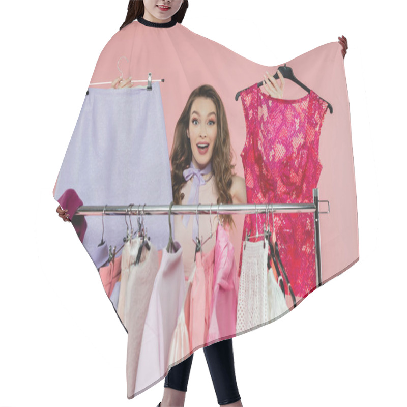 Personality  Consumerism, Amazed Young Woman With Brunette Wavy Hair Standing Near Rack With Clothes, Showing Trendy Outfit, Wardrobe Selection Concept, Beautiful Model Looking At Camera On Pink Background  Hair Cutting Cape