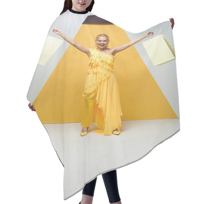 Personality  Cheerful Blonde Woman Holding Shopping Bags While Posing On White And Yellow  Hair Cutting Cape