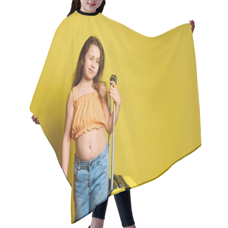 Personality  Cute Caucasian Girl Traveling Abroad, Going For Weekend Getaway, Posing With Yellow Suitcase Over Yellow Background, Winking At Camera. Children. Travel. Journey. Tourism. Summer. Holidays. Vacation Hair Cutting Cape