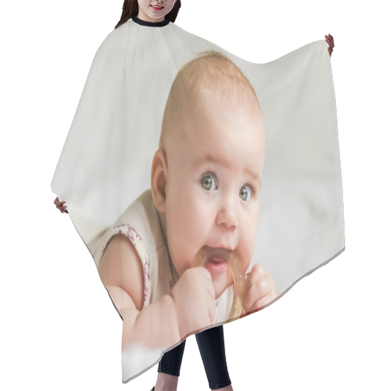 Personality  Baby Girl On Her Stomach With Teether In The Mouth Hair Cutting Cape