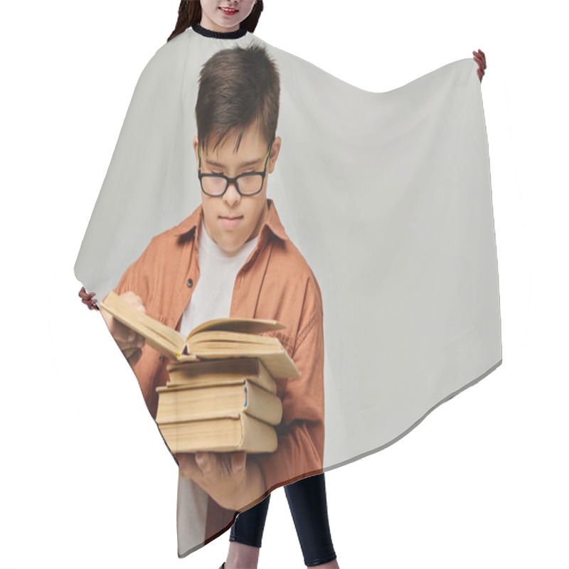 Personality  A Boy With Down Syndrome With Glasses Holds A Stack Of Books. Hair Cutting Cape