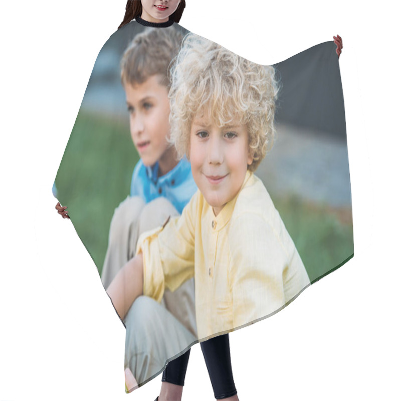 Personality  Adorable Curly Schoolboy Sitting On Grass With Classmate Hair Cutting Cape