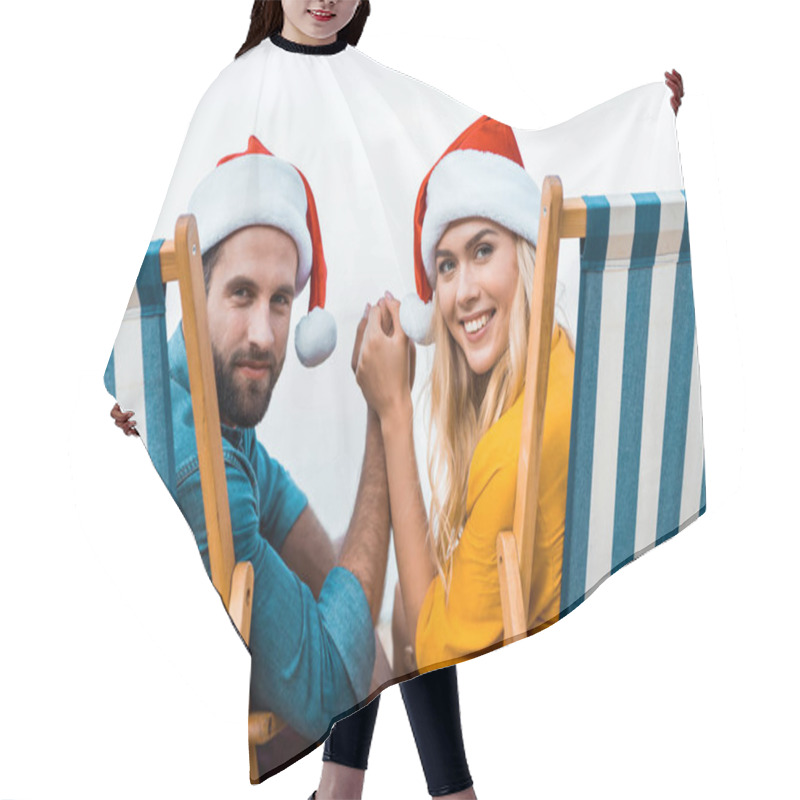 Personality  Portrait Of Couple In Santa Hats Sitting On Sun Loungers, Holding Hands And Looking At Camera On Beach Hair Cutting Cape