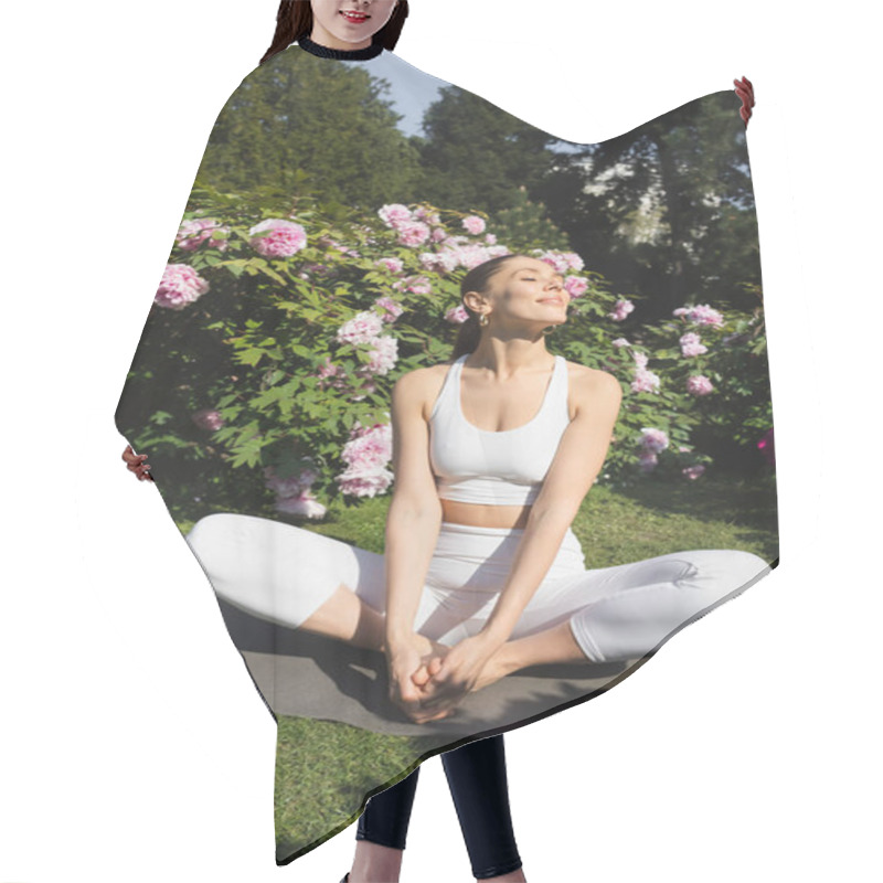 Personality  Smiling Woman With Closed Eyes Meditating In Bound Angle Pose Near Blossoming Peonies And Sports Bottle Hair Cutting Cape