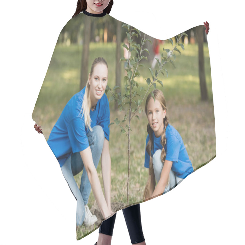 Personality  Smiling Mother And Daughter Looking At Camera While Planting Young Tree In Park, Ecology Concept Hair Cutting Cape