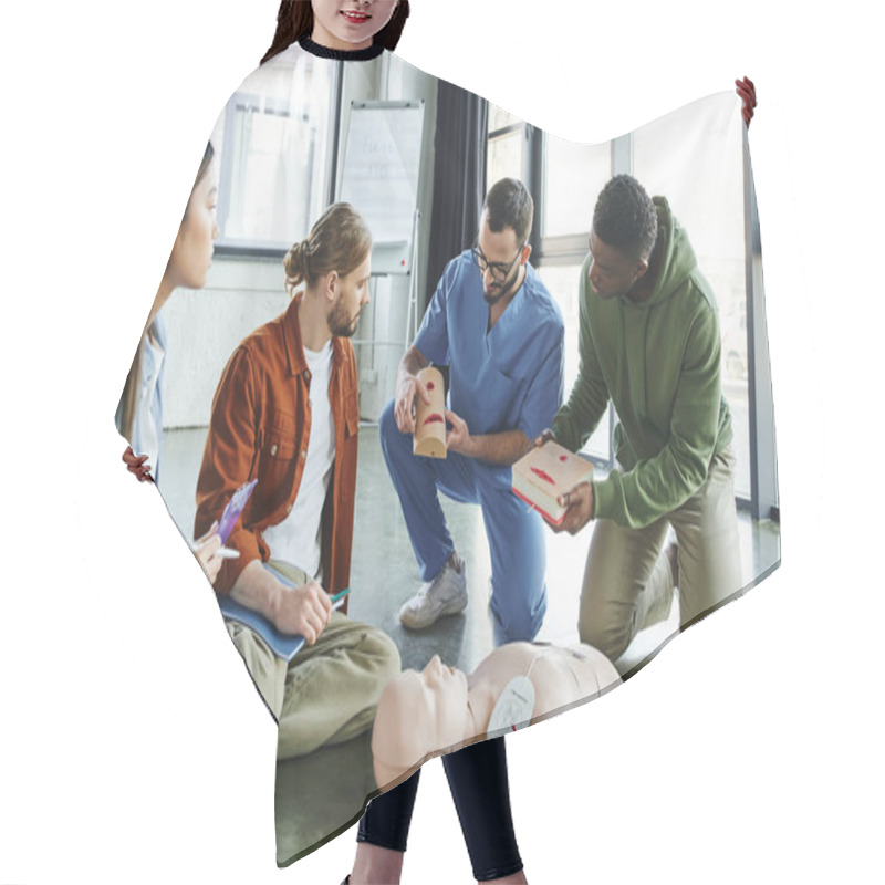 Personality  Medical Instructor And African American Man Holding Wound Care Simulators Near CPR Manikin, Defibrillator And Multiethnic Participants With Notebook And Clipboard, Life-saving Skills Concept Hair Cutting Cape