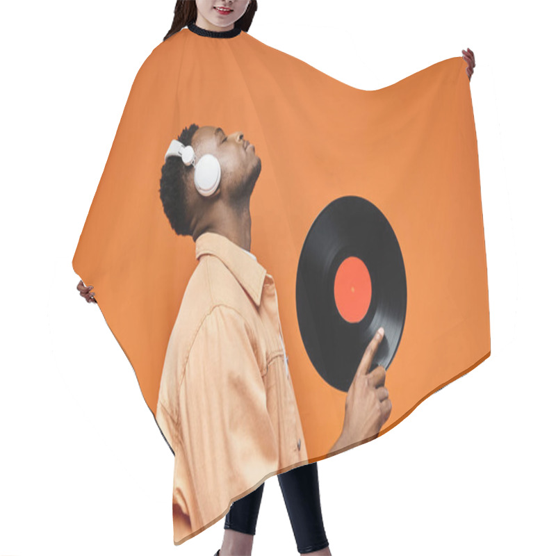 Personality  Handsome Black Man In Headphones Holds Vinyl Record Against Vibrant Orange Backdrop. Hair Cutting Cape