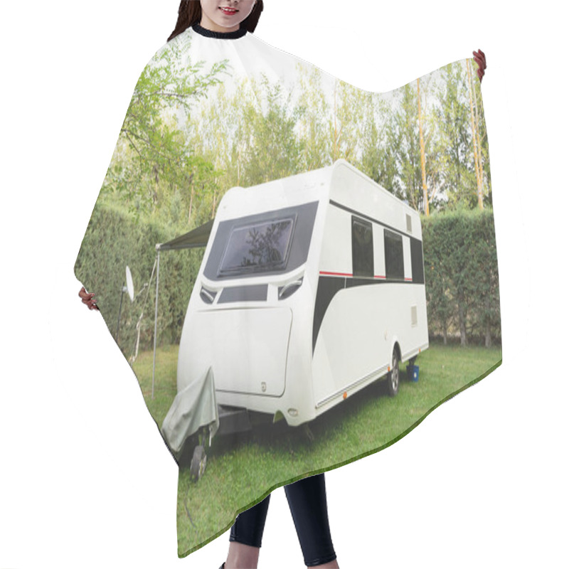 Personality  A White Trailer,a Motorhome For Travel,a Motorhome,camper,trailer Without A Car Against A Background Of Beautiful Bushes Stands On Short Green Lawn Grass.Technologies Of Transport, Means Of Travel. Hair Cutting Cape