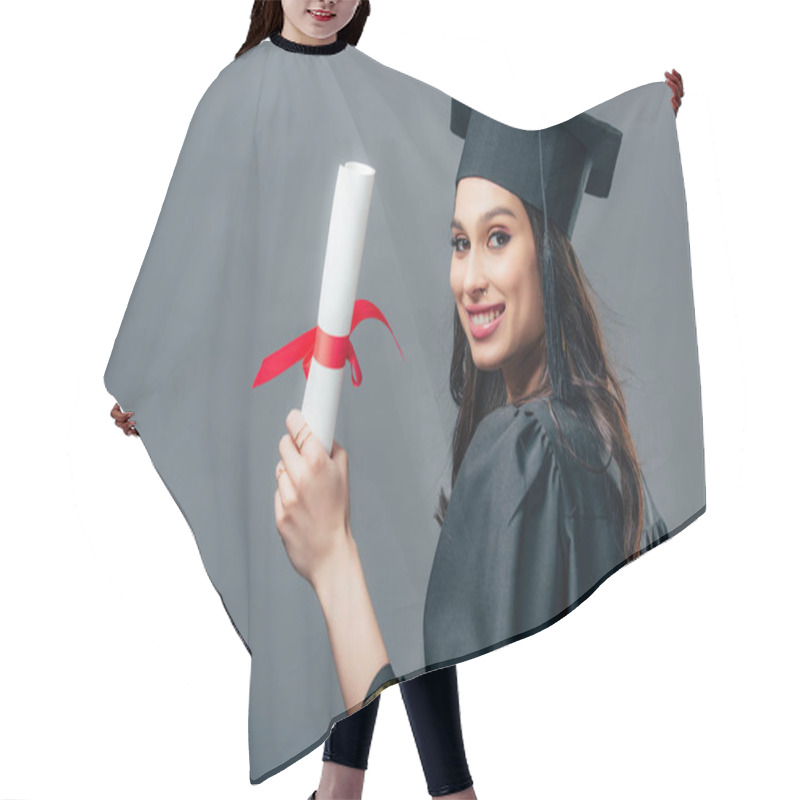 Personality  Smiling Female Indian Student In Academic Gown And Graduation Cap Holding Diploma, Isolated On Grey Hair Cutting Cape