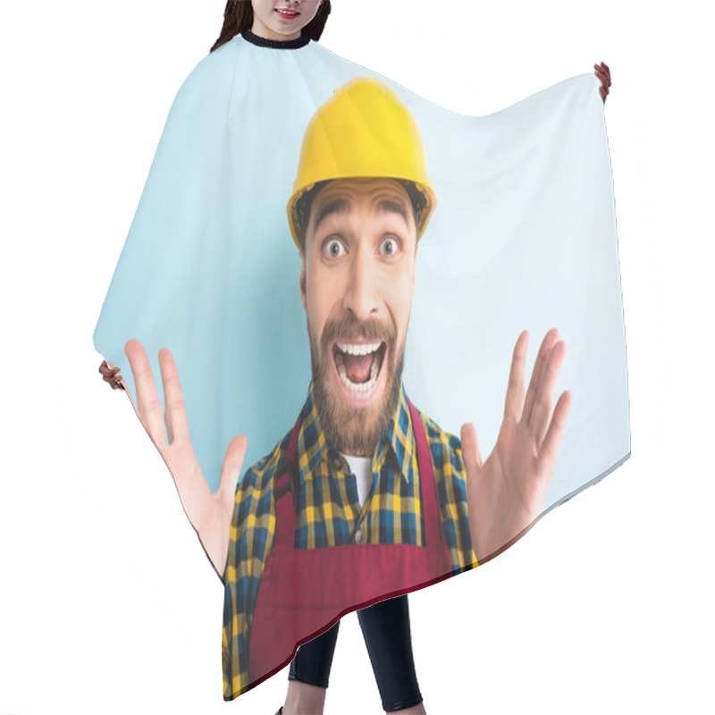 Personality  Scared Workman In Safety Helmet Looking At Camera While Screaming On Blue  Hair Cutting Cape