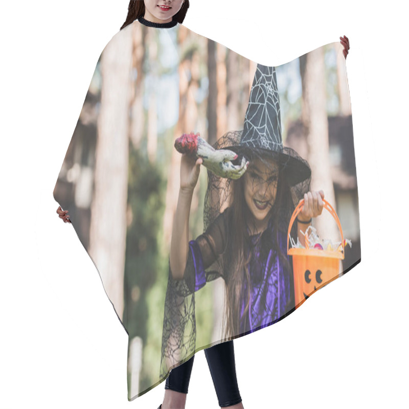 Personality  Cheerful Girl In Witch Halloween Costume Holding Toy Hand And Bucket With Sweets Outdoors Hair Cutting Cape