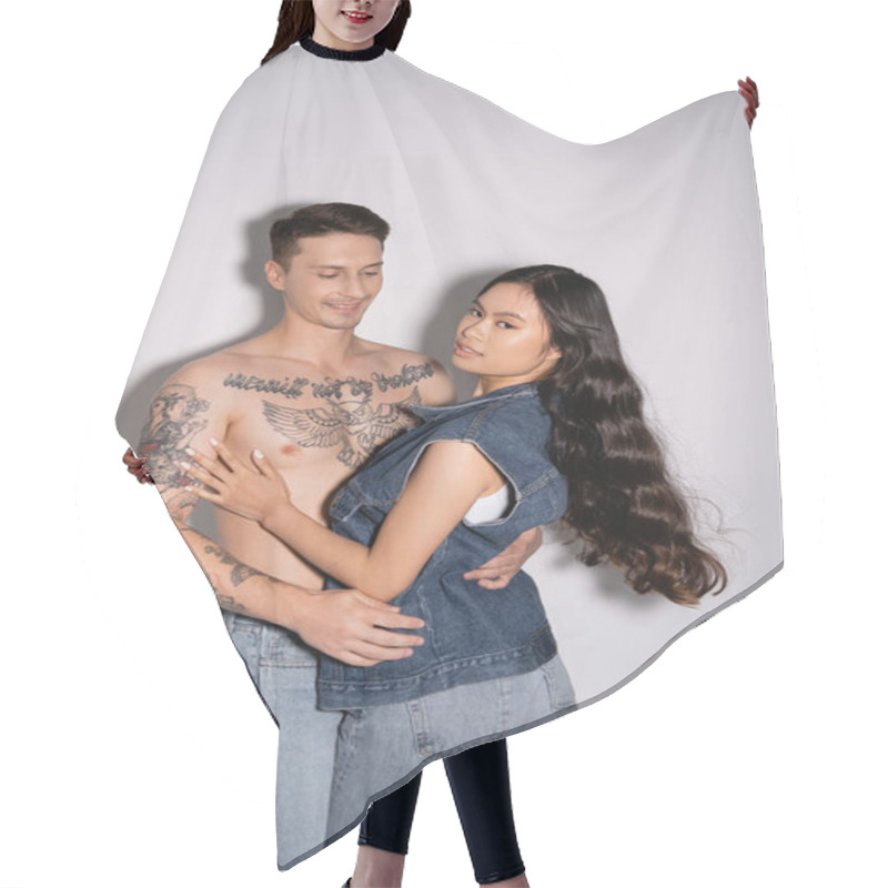 Personality  Muscular Tattooed Man Hugging Brunette Asian Woman Looking At Camera On Grey Background Hair Cutting Cape