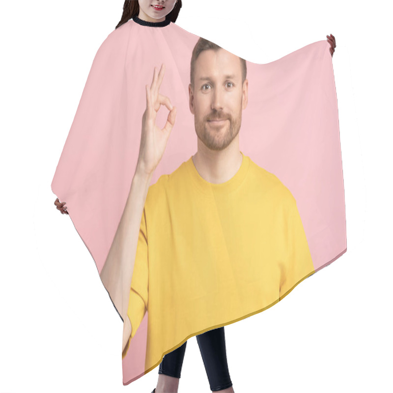 Personality  Man raises hand in gesture ok. Light smile middle aged guy in yellow T-shirt agreeing assenting shows generally arm sign, connecting index finger thumb of palm. Isolated portrait studio background. hair cutting cape