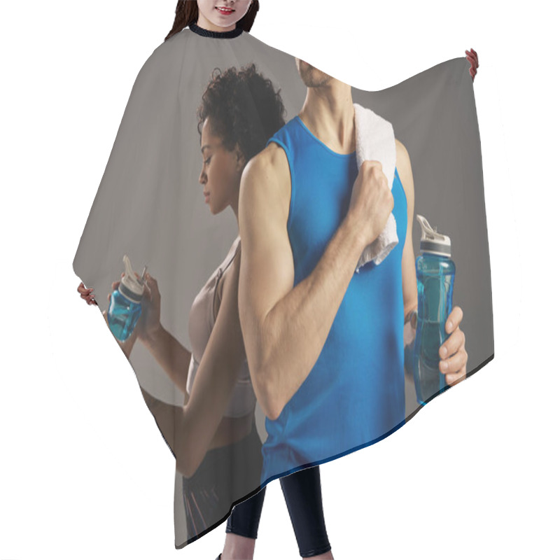 Personality  Multicultural Couple In Active Wear Holding Water Bottles In Front Of A Gray Background. Hair Cutting Cape