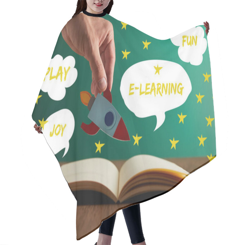 Personality  Cropped View Of Teacher Holding Rocket Over Open Book With Play, Joy, Fun And E-learning Words Hair Cutting Cape