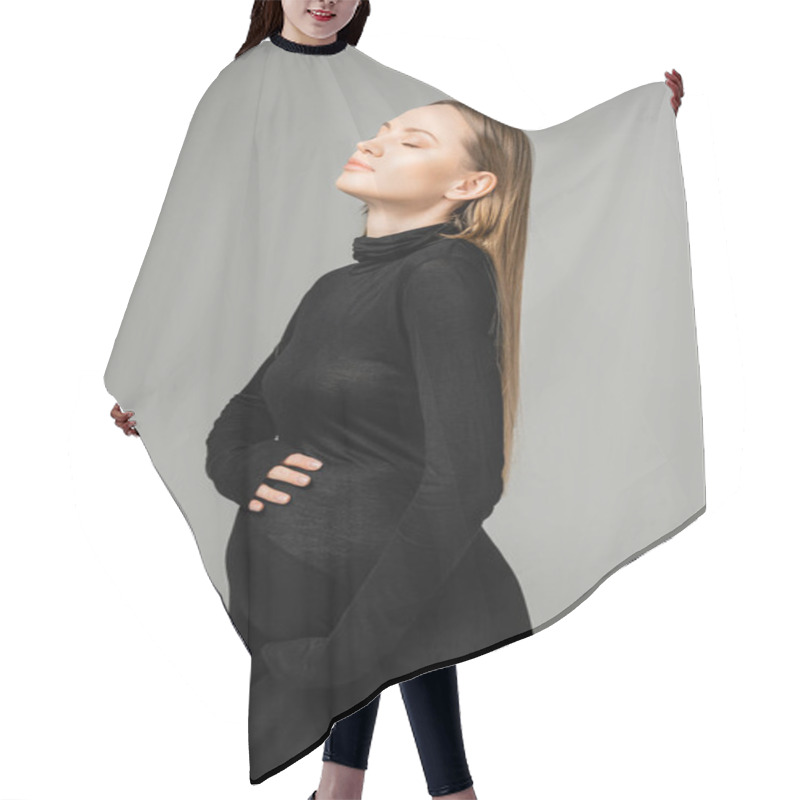 Personality  Portrait Of Long Haired And Pregnant Woman With Natural Makeup Wearing Stylish Black Dress While Touching Belly And Standing With Closed Eyes Isolated On Grey, Growing New Life Concept Hair Cutting Cape