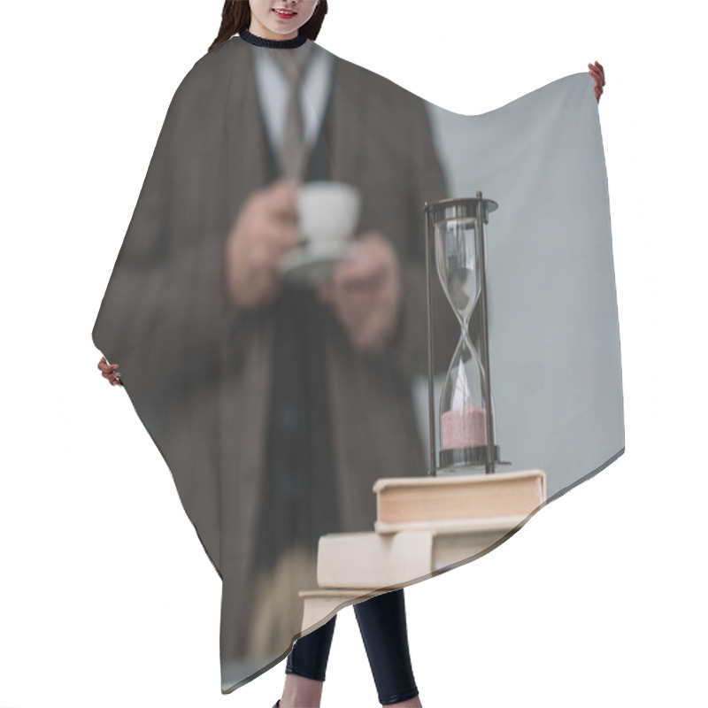 Personality  Close-up Shot Of Stack Of Books And Hourglass With Man Drinking Coffee Blurred On Background Hair Cutting Cape