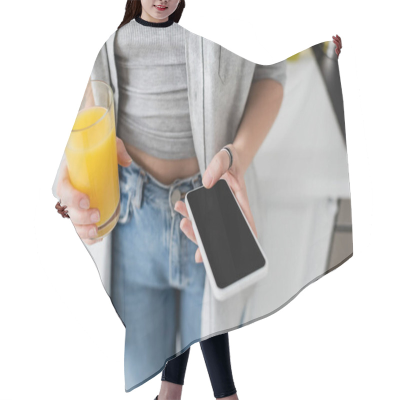 Personality  Cropped View Of Young Woman With Tattoo On Hand Holding Glass Of Fresh Orange Juice And Smartphone With Blank Screen While Standing In Casual Clothes With Blue Denim Jeans In Modern Apartment  Hair Cutting Cape