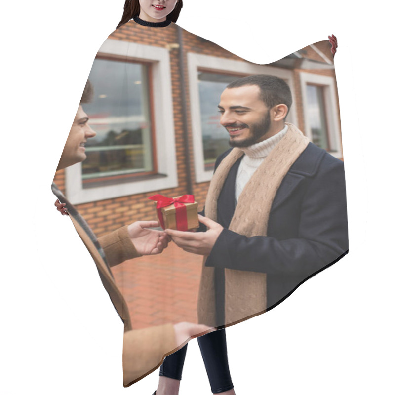 Personality  Young Gay Man Presenting Small Gift Box To Smiling Bearded Boyfriend Near Blurred Shop On Street Hair Cutting Cape