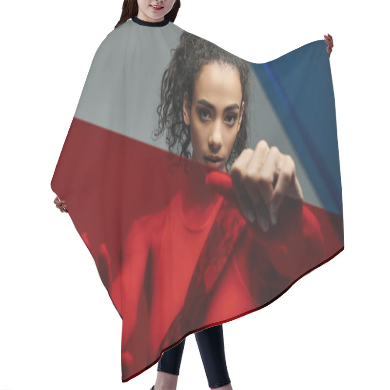 Personality  A Young Woman With Dark Curly Hair, Poses In A Studio With A Colorful Glass Pane, Looking Directly At The Camera. Hair Cutting Cape