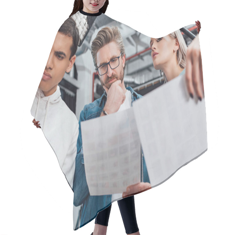 Personality  Low Angle View Of Pensive Creative Director In Glasses Looking At Photo Near Coworkers  Hair Cutting Cape