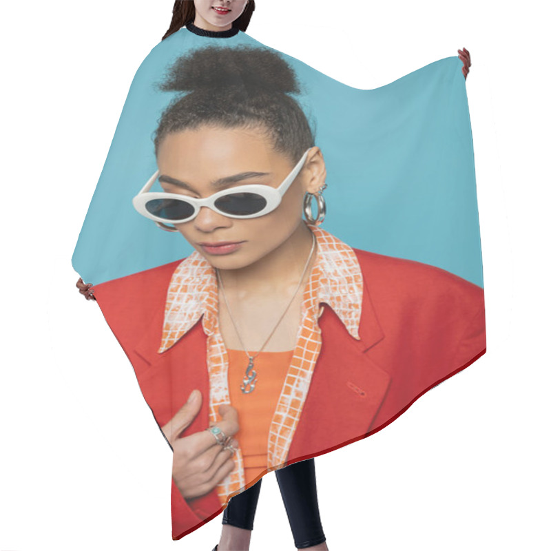 Personality  Portrait Of African American Woman In Hoop Earrings, Sunglasses And Vibrant Outfit Posing On Blue Hair Cutting Cape