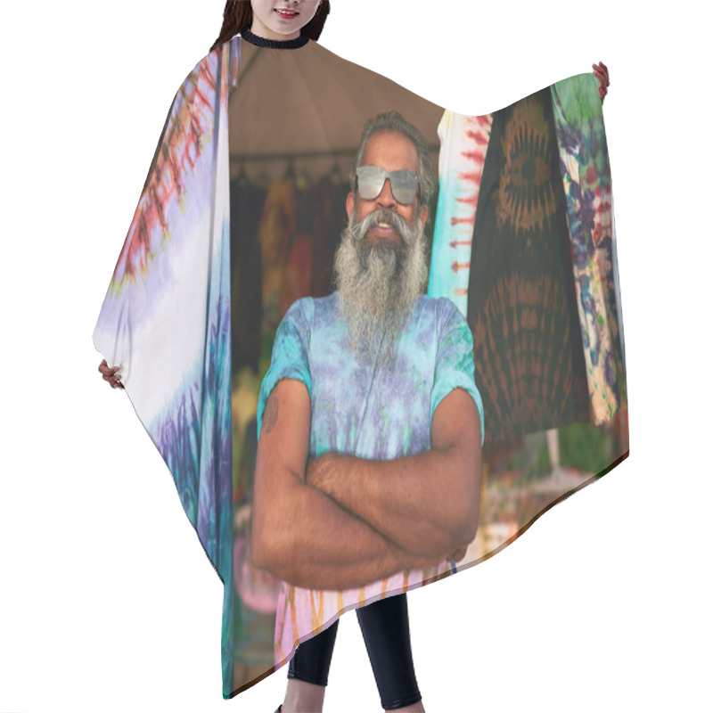 Personality  Senior Man With Long Beard Wearing Tie-dye T-shirt At Outdoor Craft Fair. Smiling, Arms Crossed, Surrounded By Colorful Clothes. Elderly Artist Shares Young Spirit Creative Lifestyle. Bohemian Event. Hair Cutting Cape