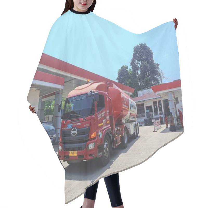 Personality  Bogor, Indonesia - 28 September 2024: A Red Pertamina Fuel Truck At A Gas Station, Ready For Fuel Delivery Under The Bright Sunlight With The Station's Red Accents Standing Out Against The Blue Sky. Hair Cutting Cape