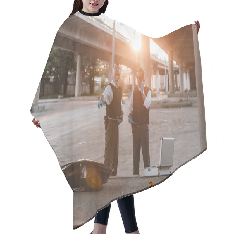 Personality  Male Police Officer In Bulletproof Vest Pointing By Finger To Colleague While He Talking On Radio Set At Crime Scene With Corpse  Hair Cutting Cape