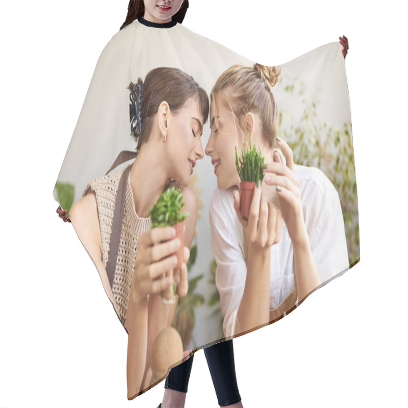 Personality  Two Women Enjoying A Serene Moment At A Table Surrounded By Potted Plants In Their Art Studio. Hair Cutting Cape