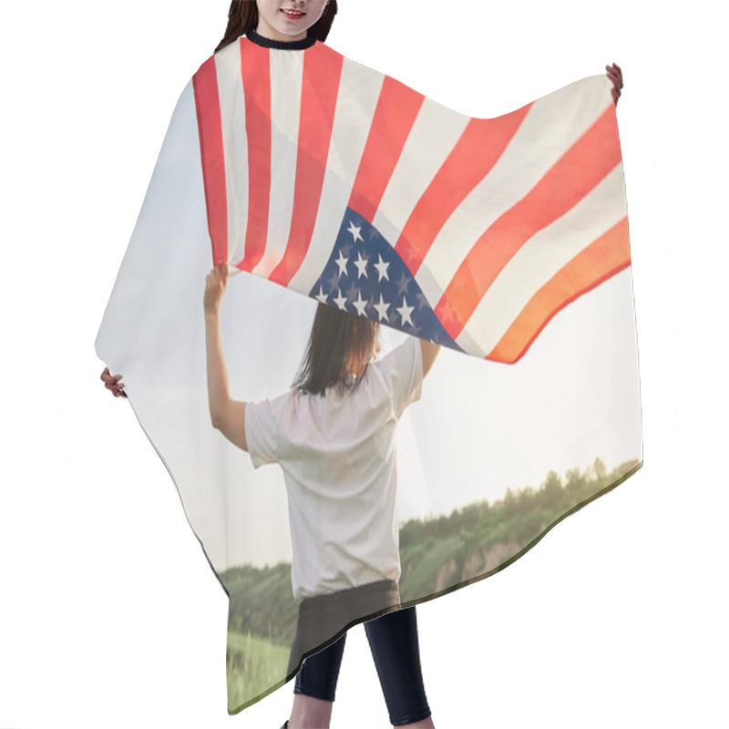 Personality  4th Of July. Fourth Of July. American Woman With The National American Flag Against Beautiful Landmark. Independence Day. Beautiful Sunset Light. Patriotic Holiday, Democracy Respect And Veteran Respect Concept Hair Cutting Cape