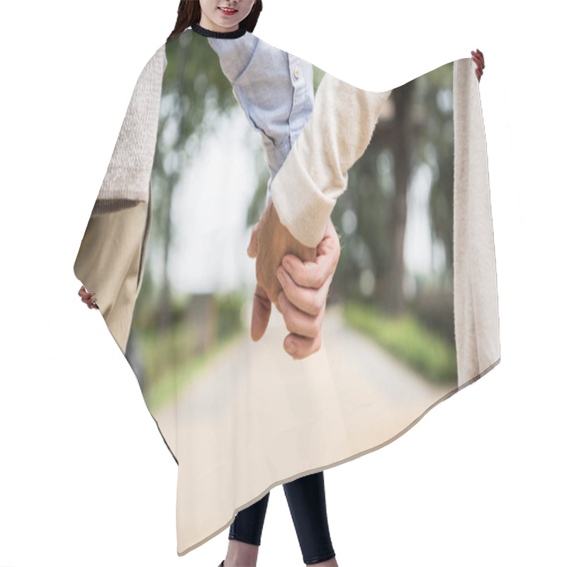 Personality  Cropped View Of Senior Couple Holding Hands While Walking In Park Hair Cutting Cape