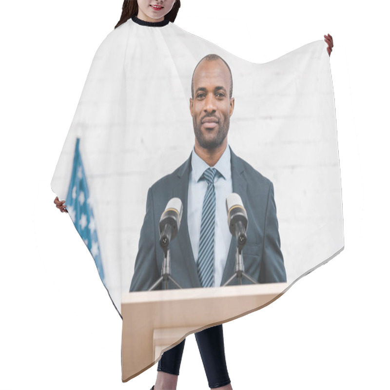 Personality  Happy African American Speaker Standing Near Microphones And American Flag  Hair Cutting Cape