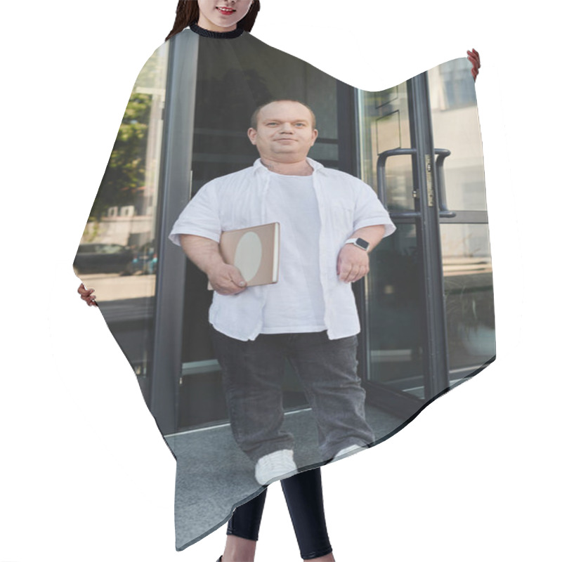 Personality  A Man With Inclusivity In A White Shirt And Black Jeans Holds A Book And Walks Out Of A Building. Hair Cutting Cape