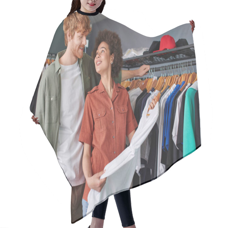 Personality  Cheerful Young African American Craftswoman Holding Clothes On Hanger Near Redhead Colleague And Standing In Print Studio At Background, Young Small Business Owners Concept  Hair Cutting Cape