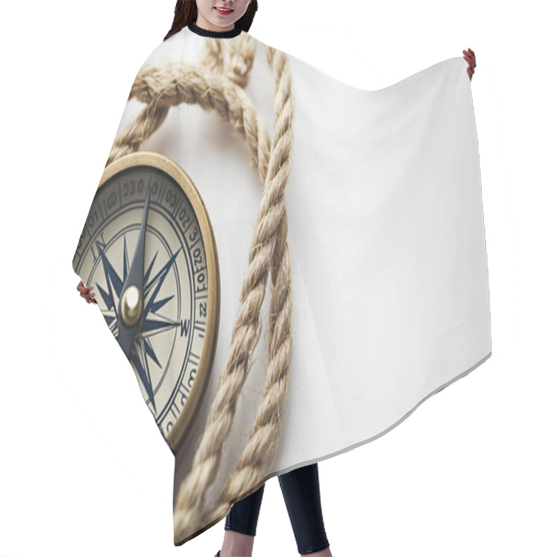 Personality  Classic Compass With A Brass Finish Entwined By A Thick Rope On A White Surface. Hair Cutting Cape