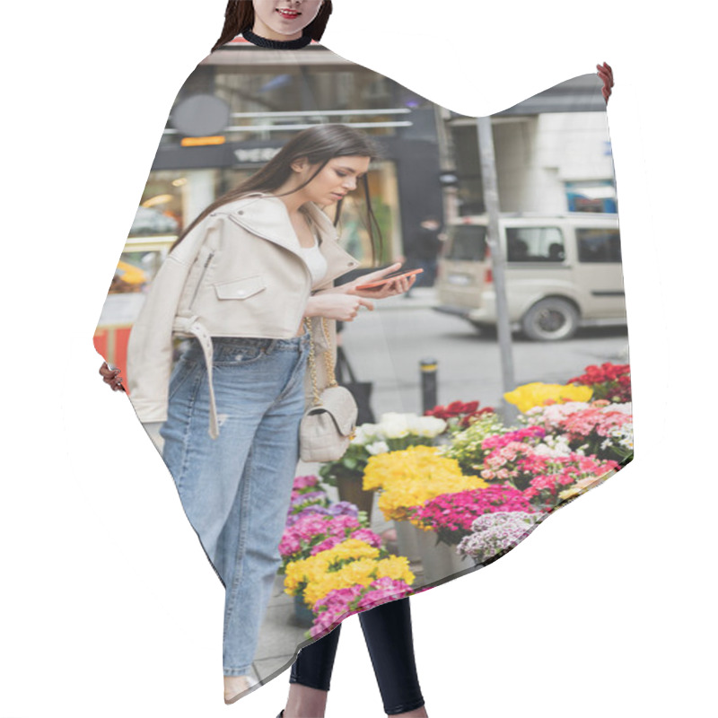 Personality  Brunette Woman With Long Hair Standing In Beige Leather Jacket, Denim Jeans And Handbag With Chain Strap Holding Smartphone While Looking At Flowers Near Blurred Cars On Street In Istanbul, Vendor Hair Cutting Cape