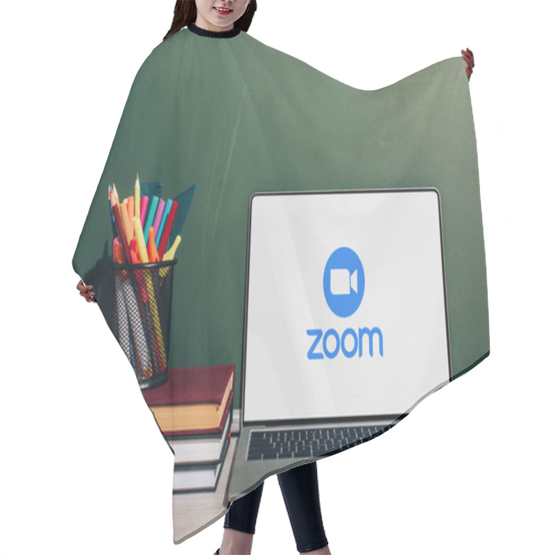 Personality  KYIV, UKRAINE - JULY 7, 2020: Laptop With Zoom Website Near Pen Holder With Stationery On Stack Of Books Near Green Chalkboard Hair Cutting Cape