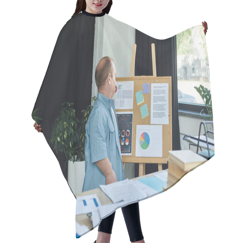 Personality  A Man With Inclusivity In A Blue Shirt Stands Near A Bulletin Board, Reviewing Charts And Data. Hair Cutting Cape