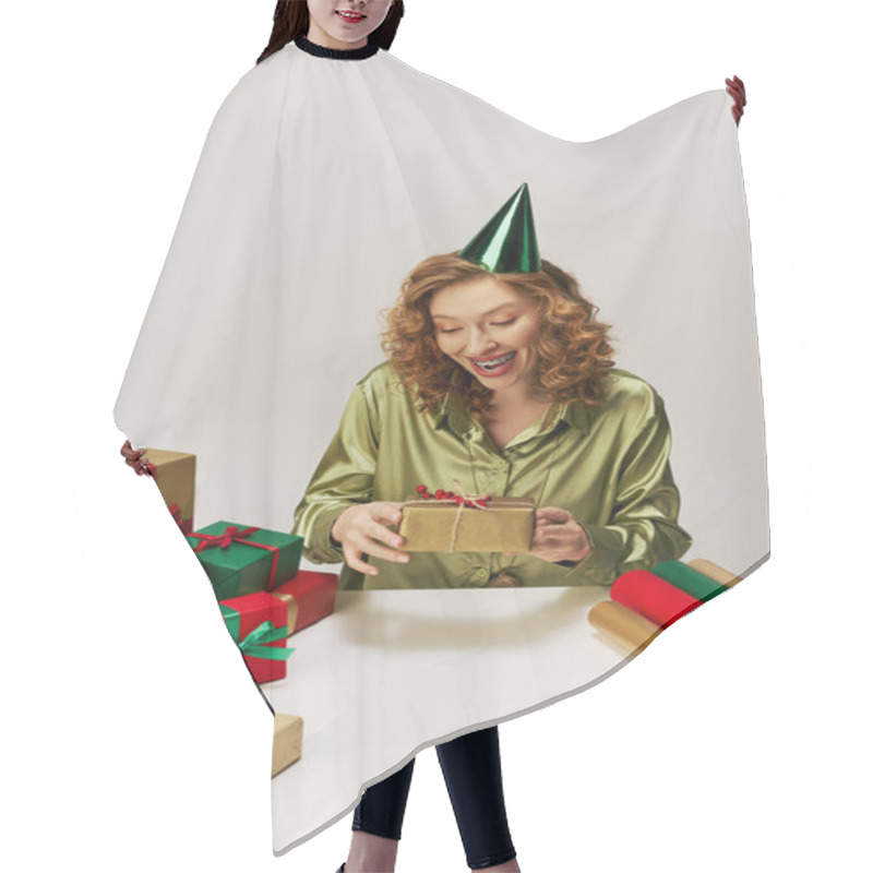 Personality  A Young Woman Wrapped In A Green Shirt Joyfully Holds Gifts While Wearing A Party Hat. Hair Cutting Cape