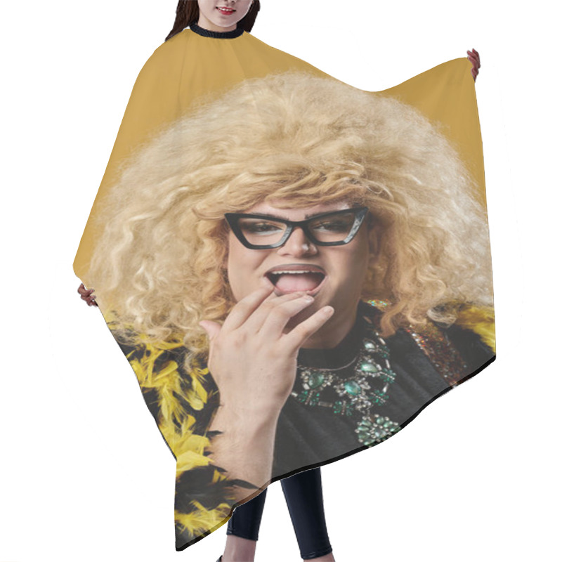 Personality  A Queer Person In A Black Top And Yellow Feathered Boa Smiles Against A Yellow Background. Hair Cutting Cape