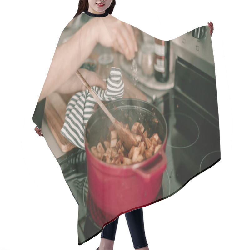 Personality  Lady Cooks Dinner For Family. Dutch Oven On Stove Top. Lifestyle Kitchen. Stewed Potatoes. Seasoning With Salt, Stiring Meal. Hot Meal. Cook Process. Dinner Preparation. Kitchen Towel. Red Dutch Oven Hair Cutting Cape